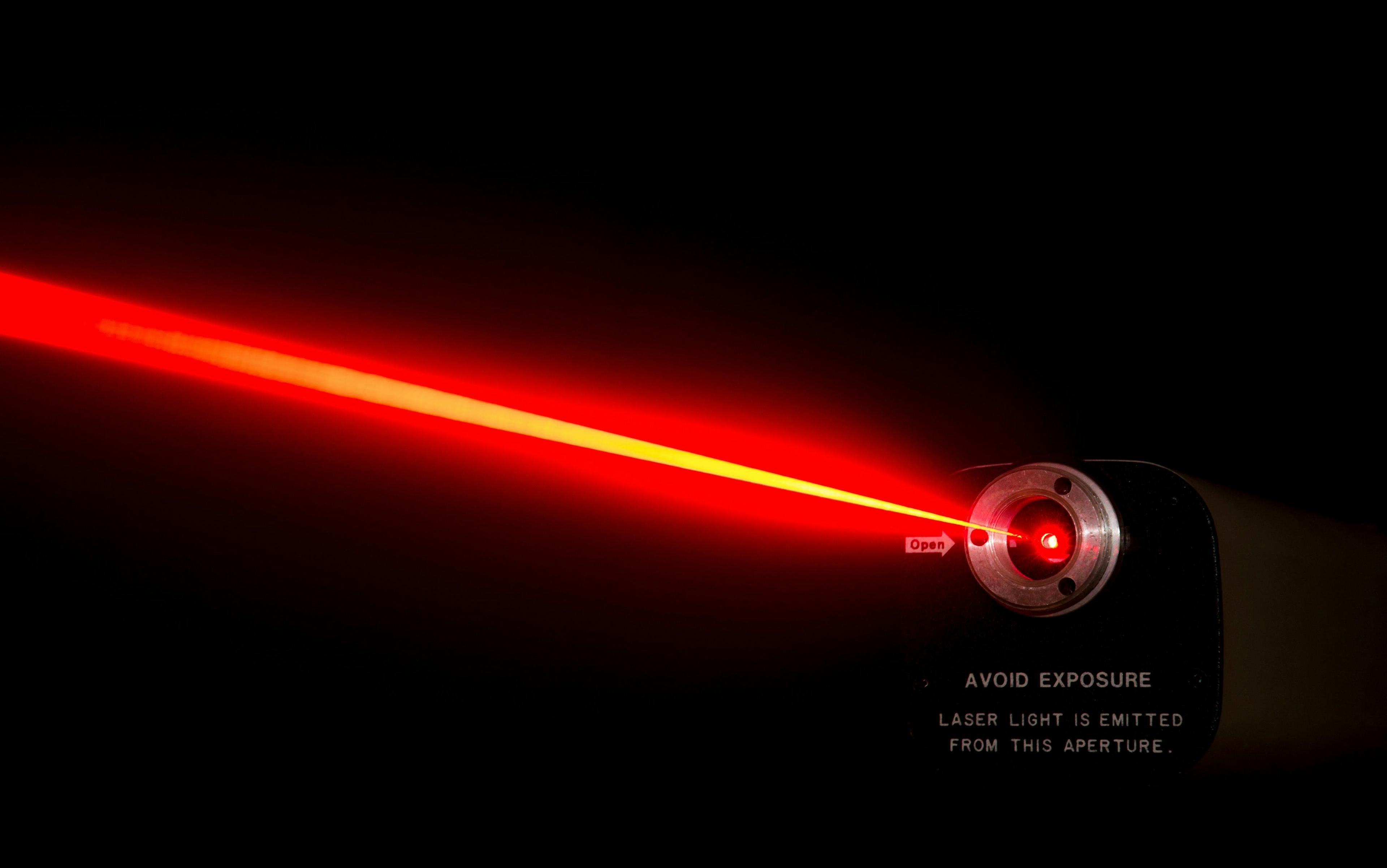 Red laser beam from a lab laser. Warning notice on front. Black background. | Image Credit: © madscinbca - stock.adobe.com