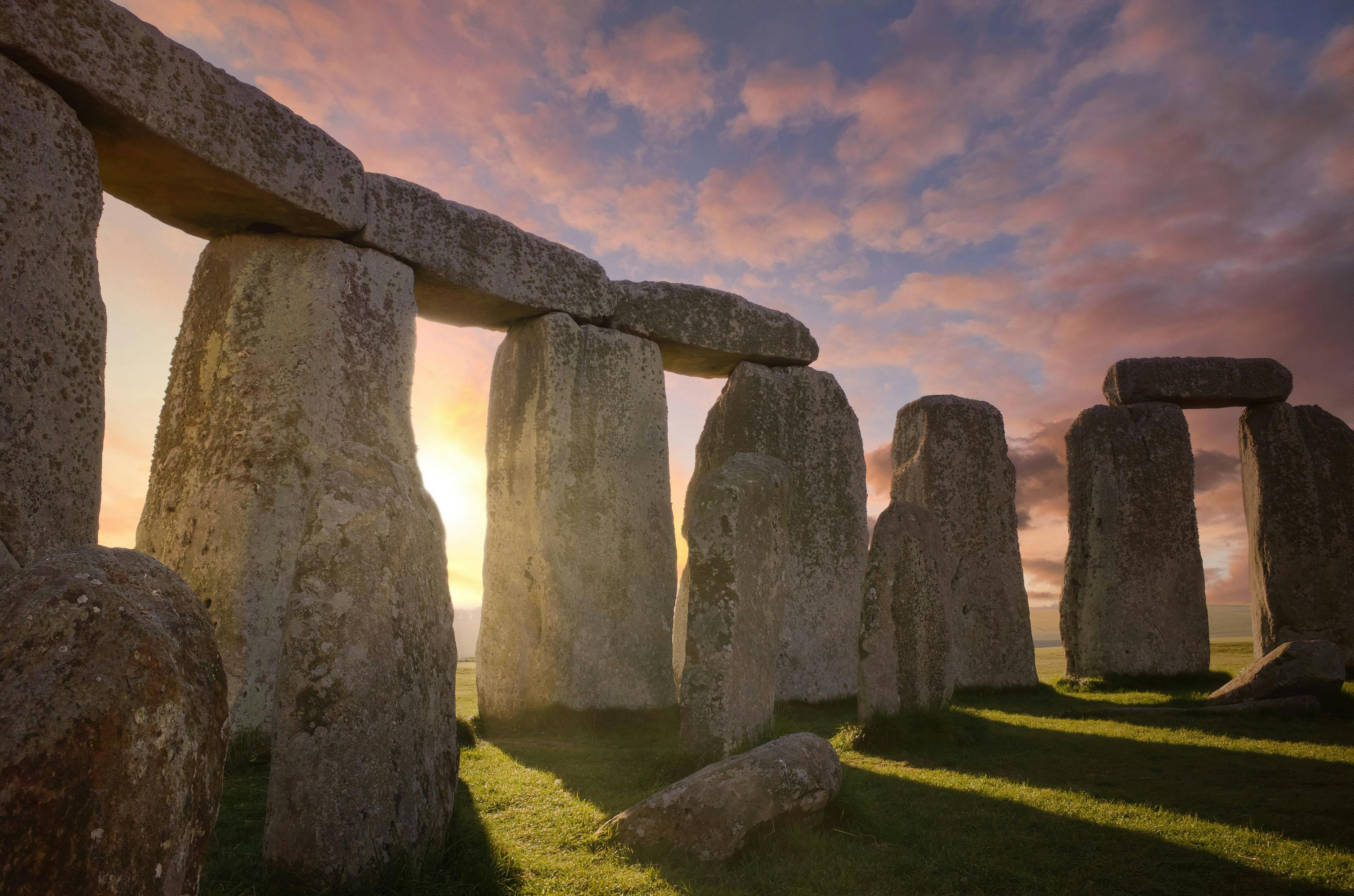 Inside the Stonehenge Circle of Stones with a Sun Rays Filtering Through the Arches Dramatic Sky Sunrise behind it | Image Credit: © PTZ Pictures - stock.adobe.com