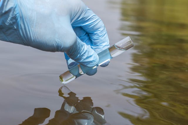 Sample water from the river for analysis. Hand in glove holding | Image Credit: © adragan - stock.adobe.com