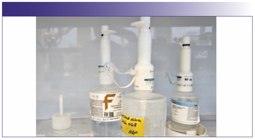 FIGURE 2: PFA ultra-high purity acid bottles that have been repurposed as high purity acid dispenser bottles. The bottletop dispensers also have 100% PFA liquid path. The vessels are inside a polypropylene laminar flow hood to prevent sample contamination during preparation.
