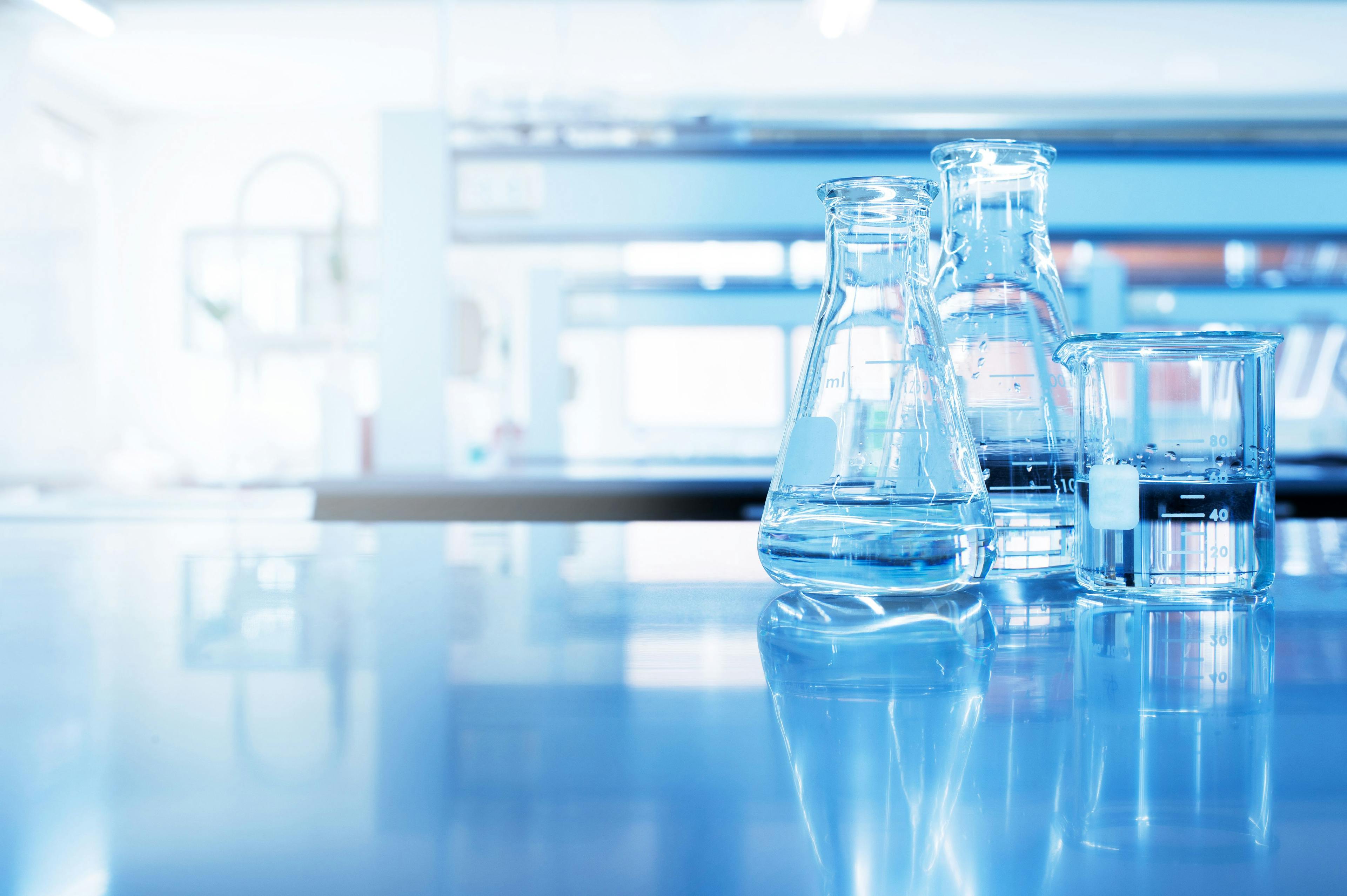 water in beaker and flask glass in chemistry blue science laboratory background