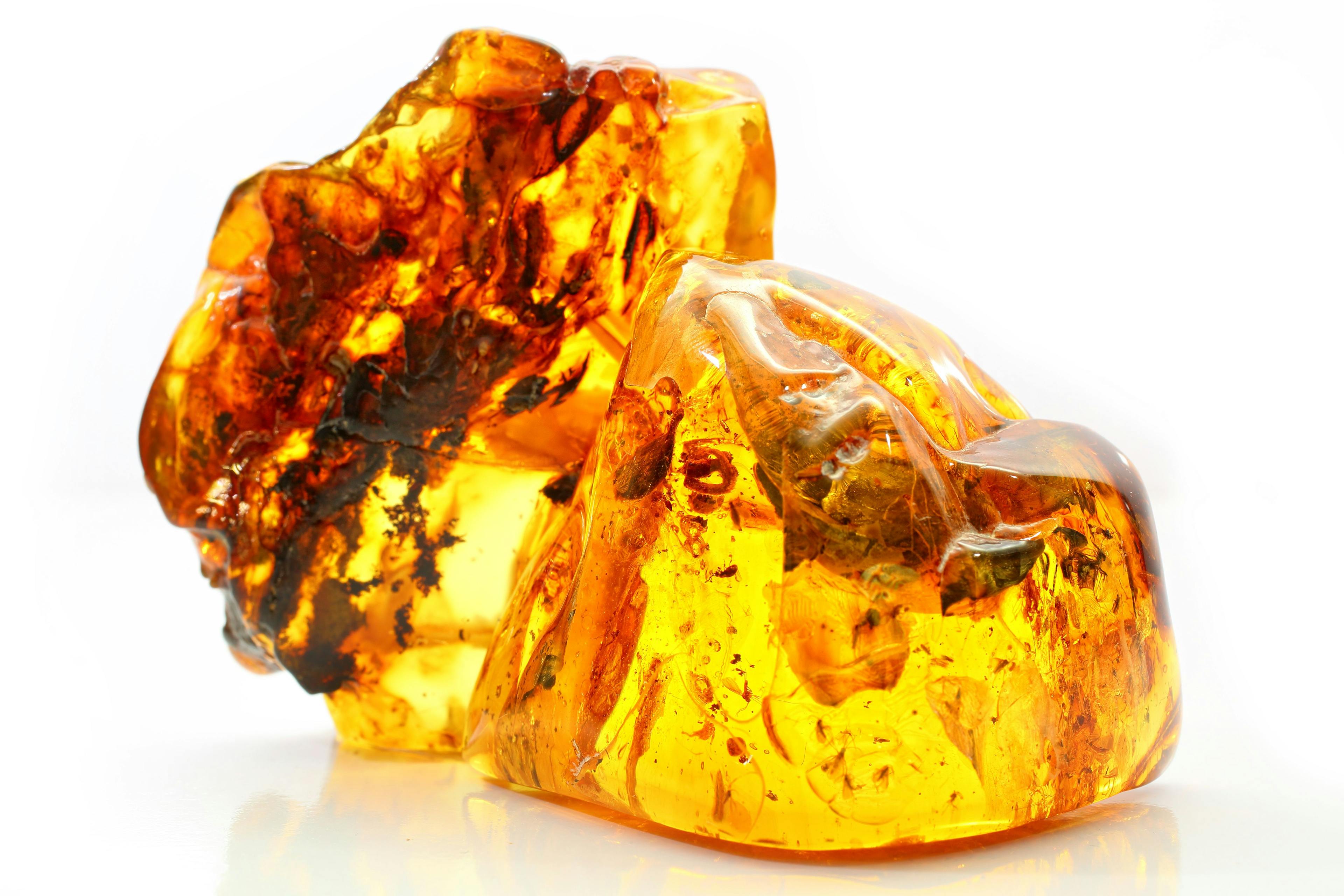 Natural amber. Two extraordinarily beautiful pieces of transparent yellow amber with inclusions on a white background with a bokeh effect. A natural mineral for jewelry. Color texture of sunstone | Image Credit: © IGOR - stock.adobe.com