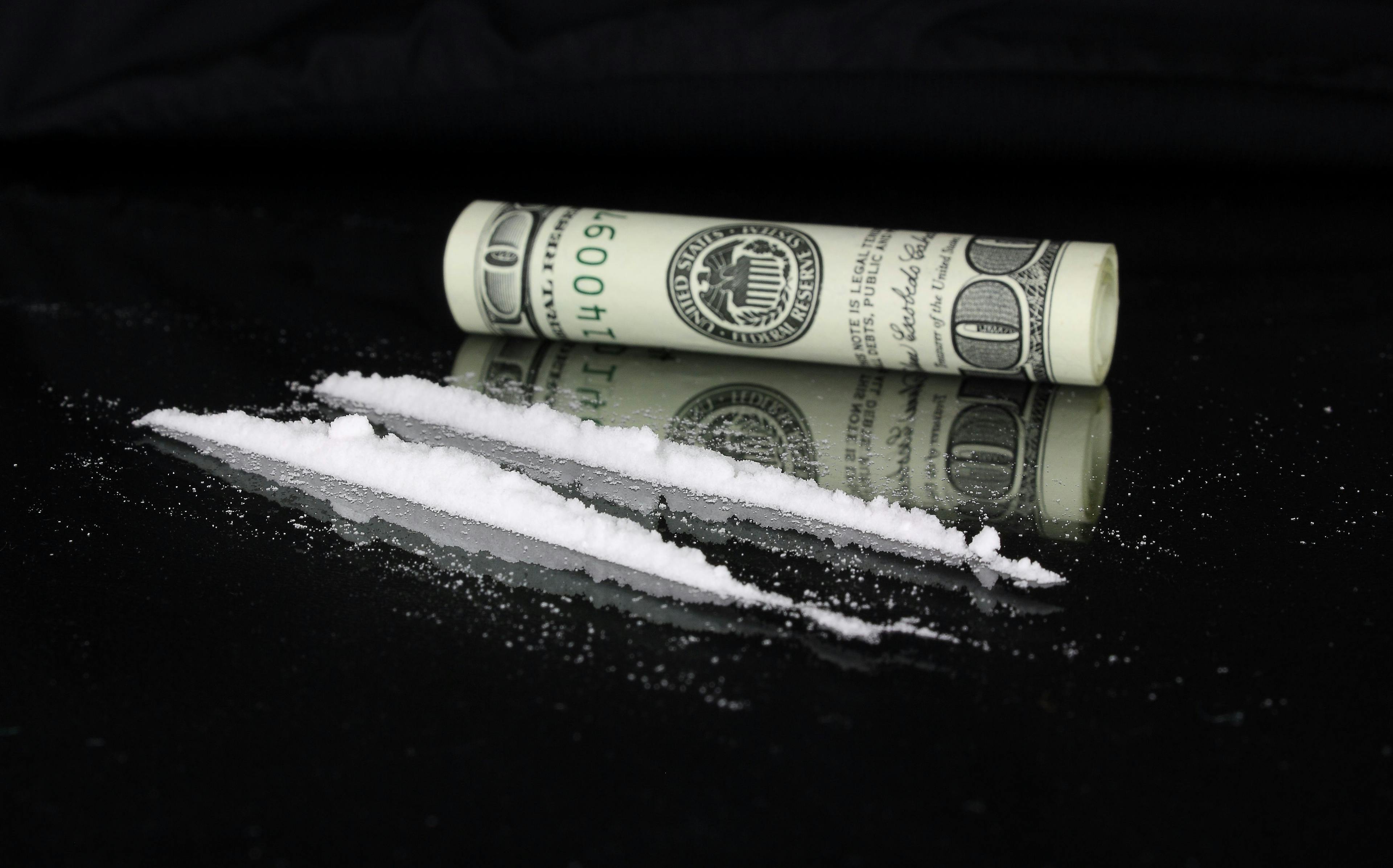 two lines of cocaine next to a rolled-up $100 bill