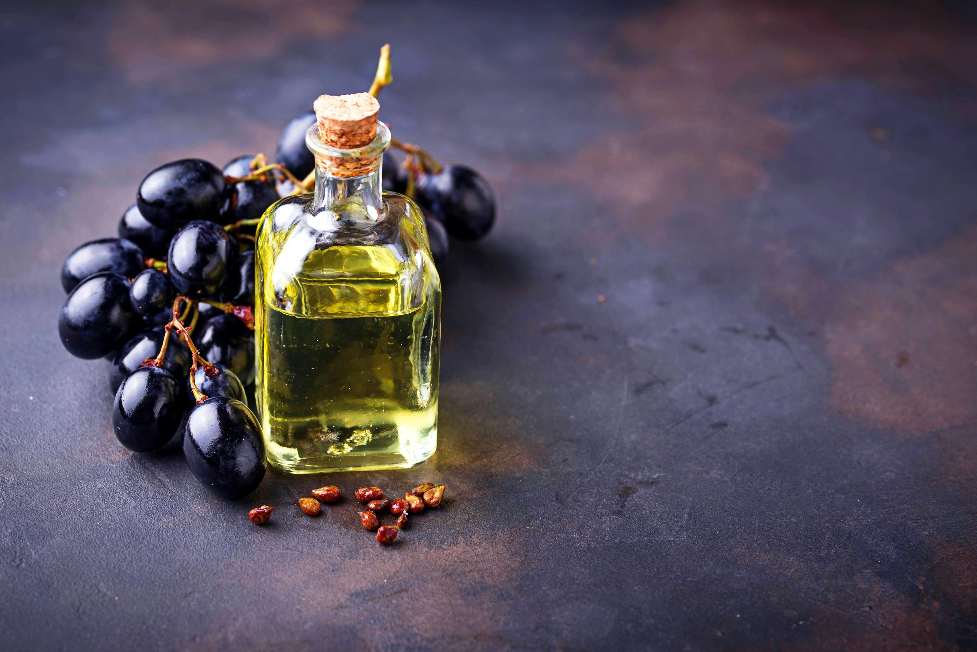 grape seed oil in a bottle with grapes surrounding it