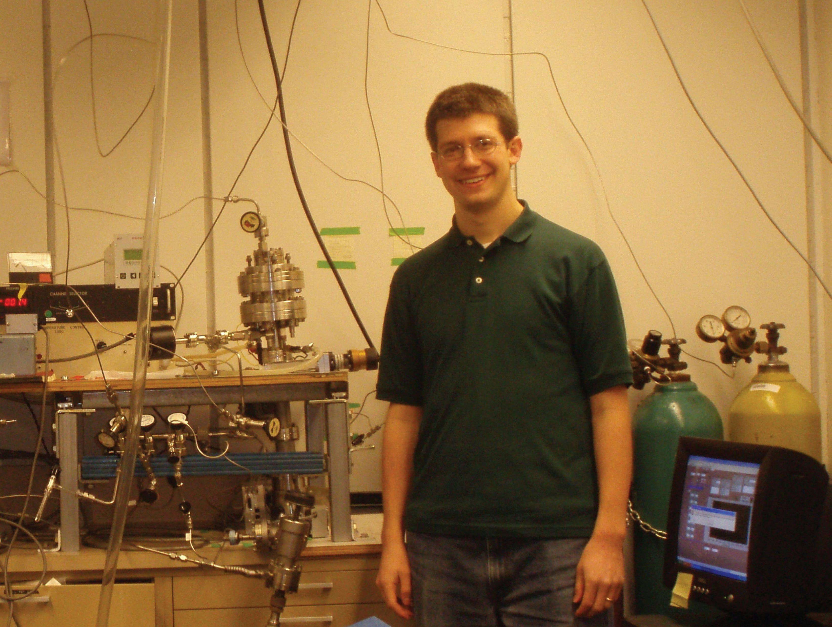 FIGURE 5: Baker as a graduate student in Gabor Somorjai’s laboratory at University of California, Berkeley in 2011. Shown in the background is the hot electron nanodiode reactor.