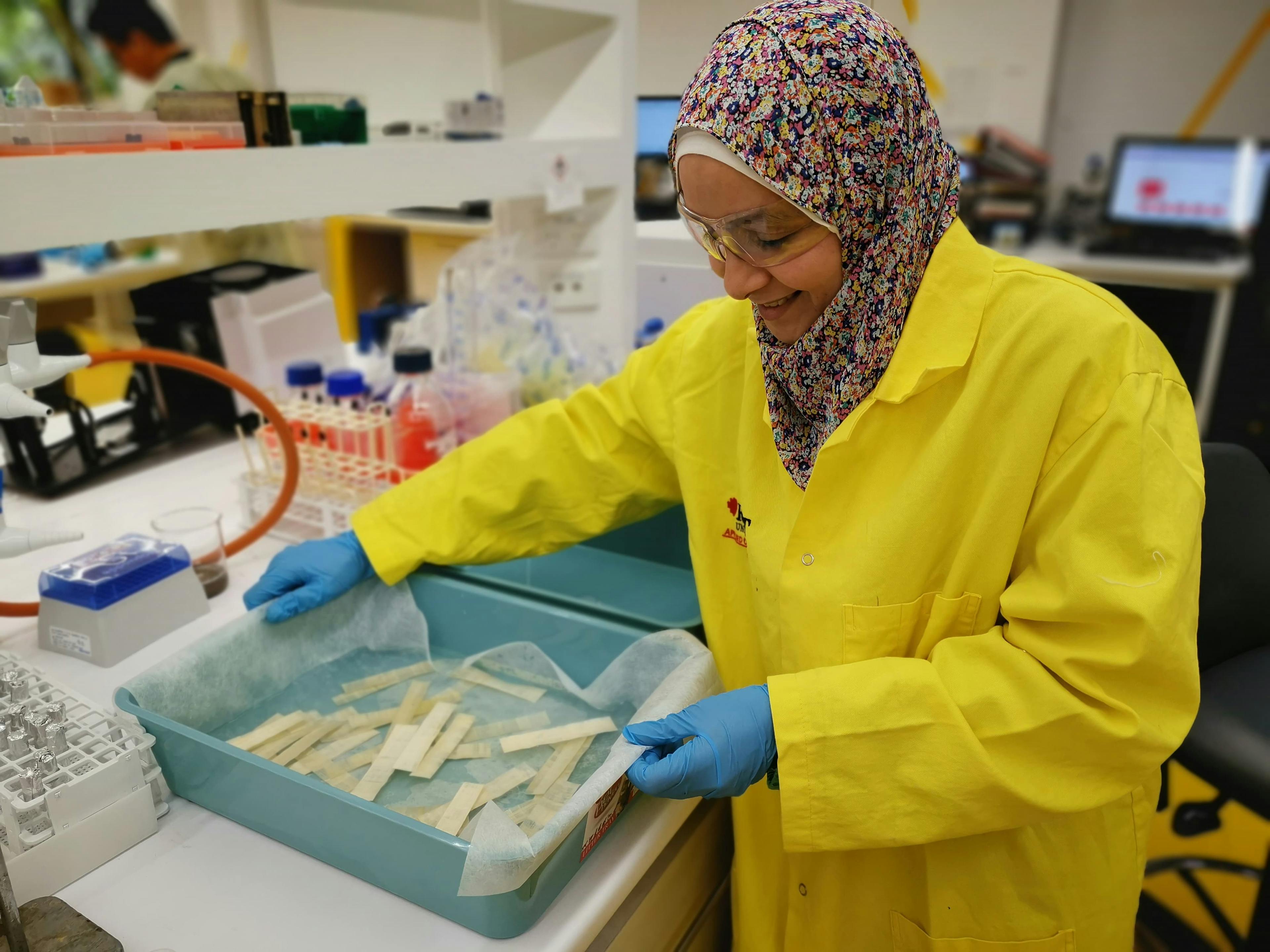 Arzak Mohamed handling fragile papyrus during her work. To analyze the papyrus, she uses X-ray fluorescence spectroscopy and scanning electron microscopy with energy-dispersive X-ray spectroscopy (SEM-EDS). Image Credit: Arzak Mohamed.