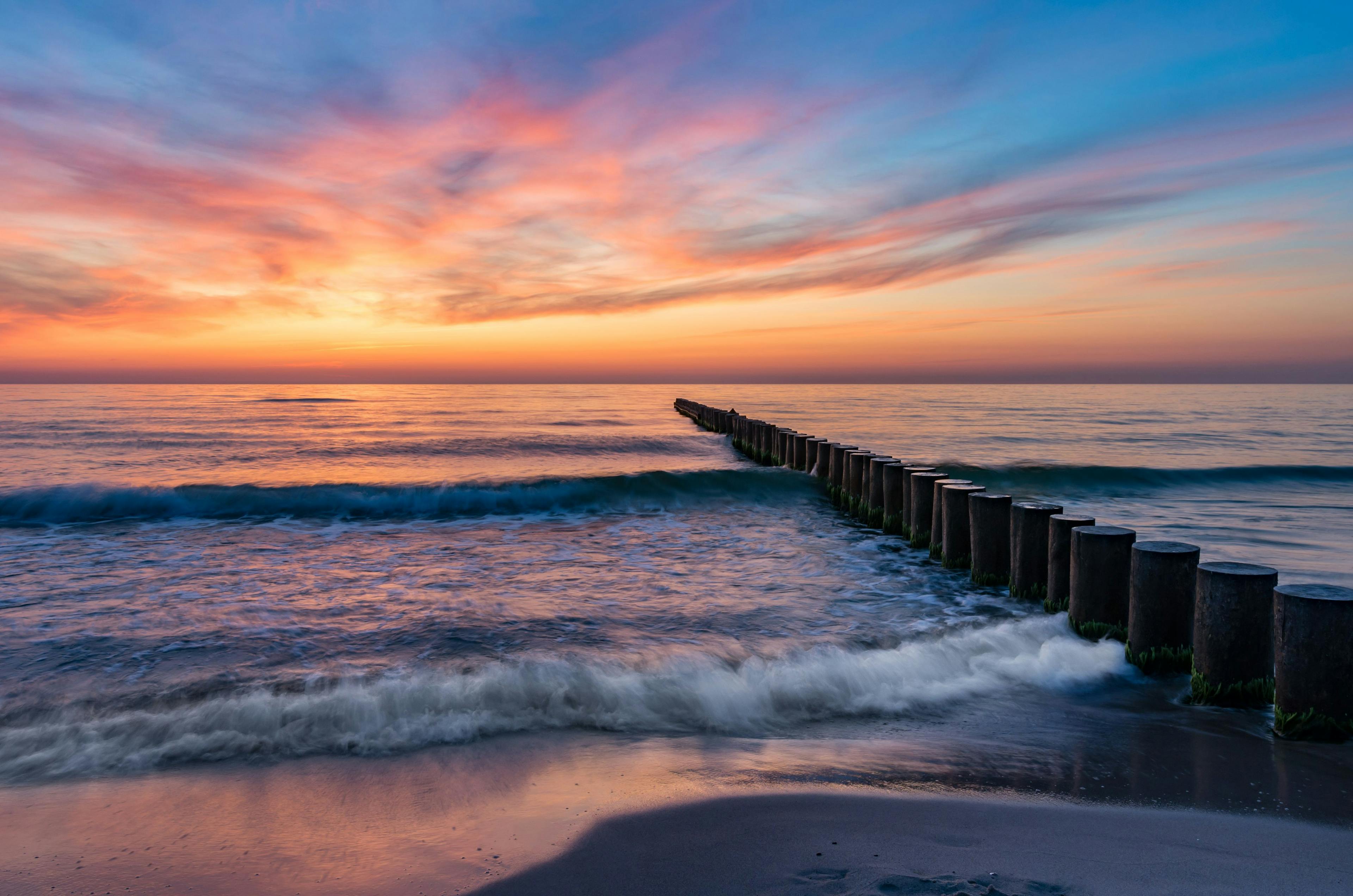 Baltic sea seascape at sunset, Poland, wooden breakwater and waves | Image Credit: © tomeyk - stock.adobe.com
