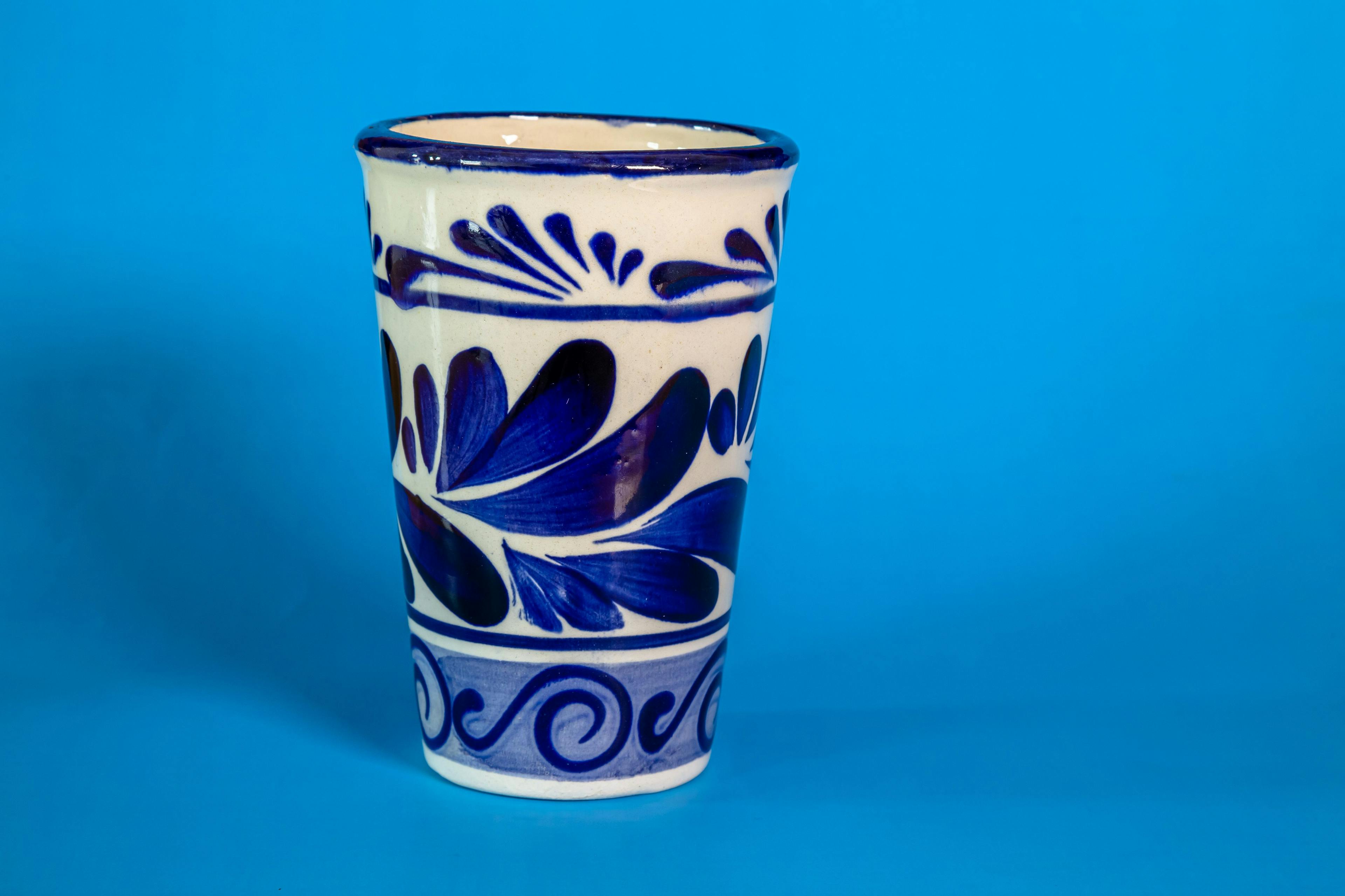 A close up of a Talavera cup with a blue background.


