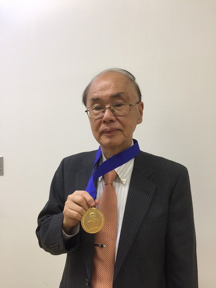 A professor holding a golden medal