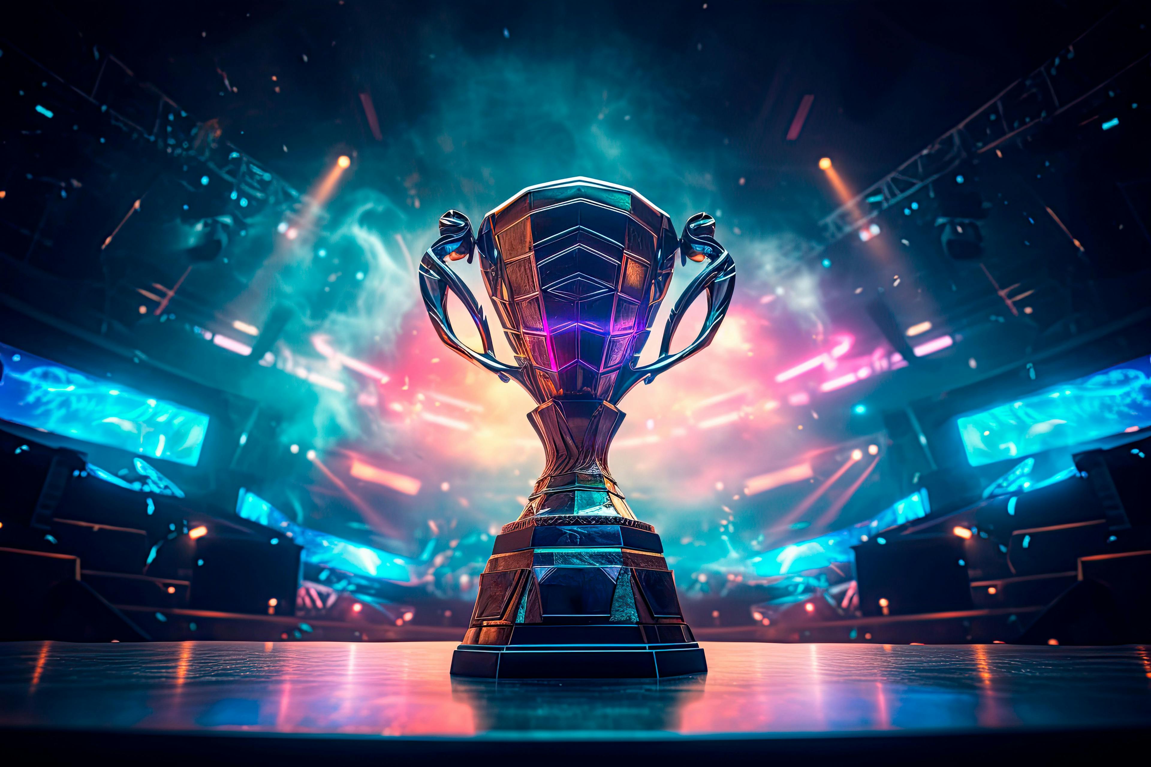 The esports winner trophy standing on the stage in the middle of the arena of the computer video game championship. Two rows of PCs for competing teams. Stylish neon lights with a cool design. | Image Credit: © Александр Марченко - stock.adobe.com. 