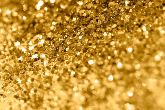Pile of shining gold pieces seen from above. Top view macro image of sparkling gold dust for backgrounds and textures. Selective focus and shallow depth of field. | Image Credit: © Ole - stock.adobe.com
